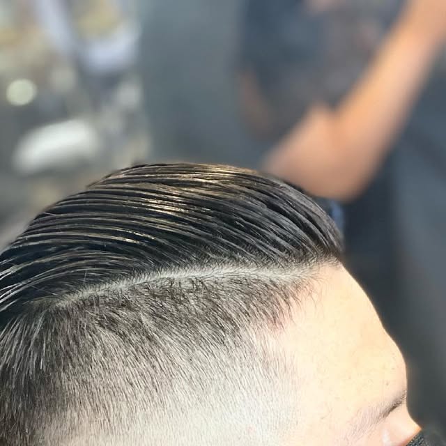 Slicked side part with a razored hard line and a skin fade